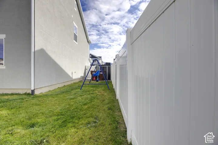 Side yard featuring a grass lawn and a full-height white vinyl privacy fence