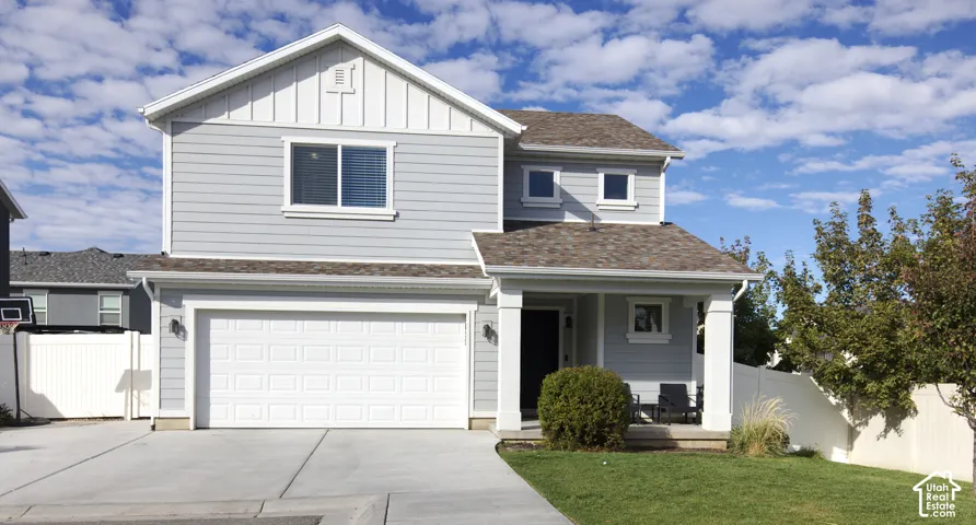 Two-story residence featuring horizontal lap siding, vertical board-and-batten gable accents, a covered front porch with squared columns, and a double-bay attached garage