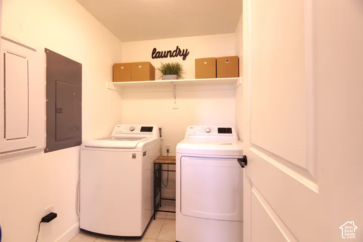 Laundry room same floor as Bedrooms featuring a single-tier white shelf, tile flooring, and integrated electrical service panel