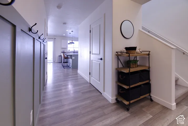 Entryway featuring gray board-and-batten wall detailing with mounted hardware, wood-finish flooring, two-panel interior doors, and a staircase with a handrail