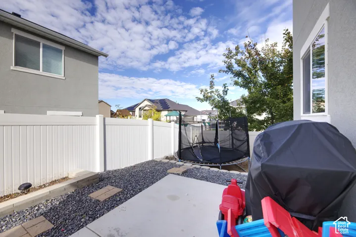 Low-maintenance side yard featuring a concrete patio, stone-aggregate ground cover, and a solid white vinyl privacy fence