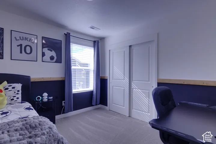 Room featuring neutral carpeting, a dual-panel sliding closet door, and a single window with wood-trim chair rail detailing
