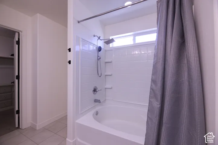 Primary Bathroom featuring a deep soaking tub, tile surround, integrated shelving, handheld showerhead, and upper horizontal window
