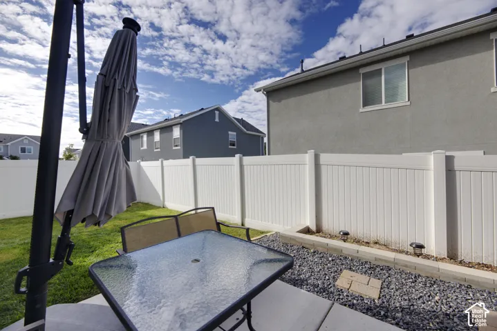 Fenced backyard featuring a concrete patio, a stone-bordered gravel area, and a lawn