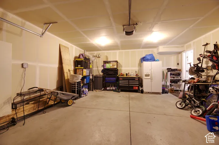 Multi-car garage featuring a concrete floor, finished drywall, and ceiling-mounted garage door opener