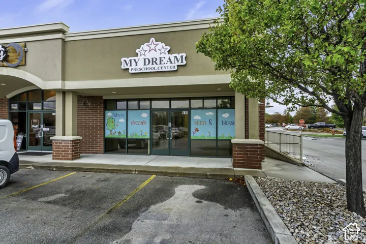 Commercial storefront featuring a brick and stucco facade, expansive glass entry doors, floor-to-ceiling windows, and dedicated parking