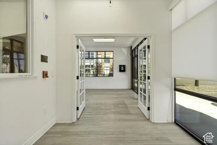 Interior space featuring light wood-finish flooring, white double French doors, large picture windows, and recessed ceiling lighting