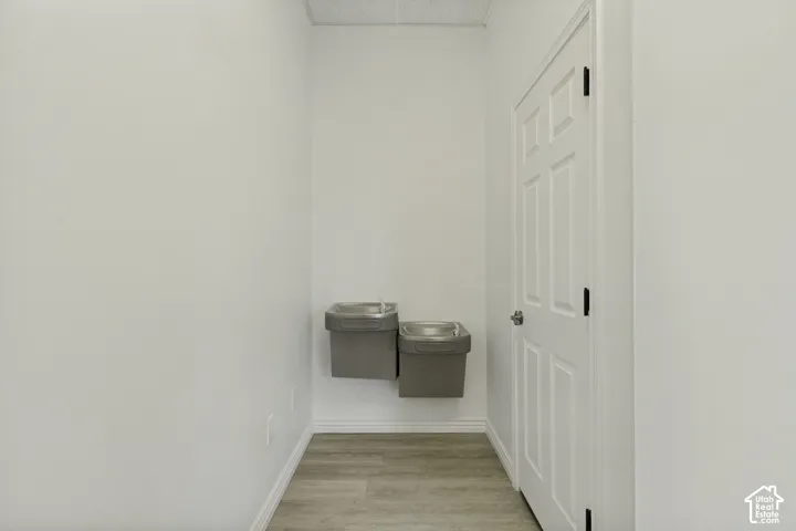 Dual wall-mounted stainless steel water stations, wood-finish flooring, and a six-panel interior door