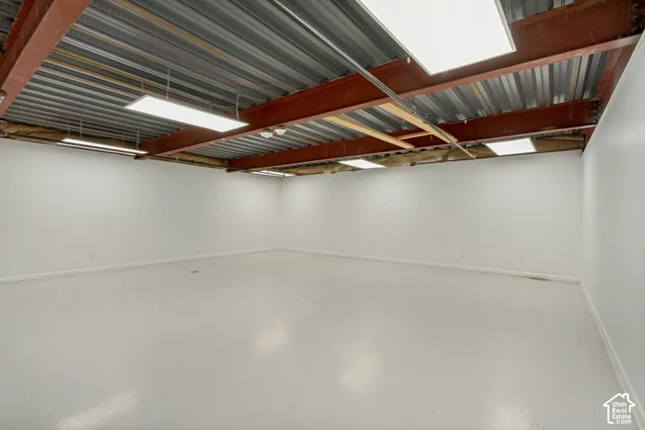Industrial-style interior featuring an exposed steel beam ceiling, corrugated metal decking, smooth finished flooring, and recessed panel lighting