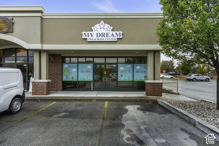 Commercial storefront featuring a brick and stucco facade, recessed entry, full-height glass display windows, and dedicated asphalt parking