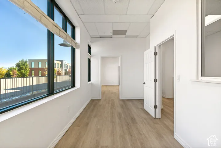 Interior space featuring wood-finish flooring, floor-to-ceiling windows with black frames, and neutral wall tones