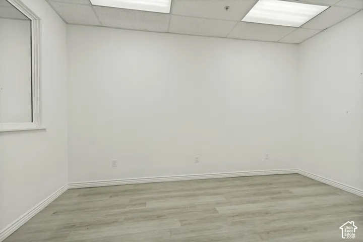 Interior space featuring light wood-finish flooring, drop ceiling panels, and recessed panel lighting