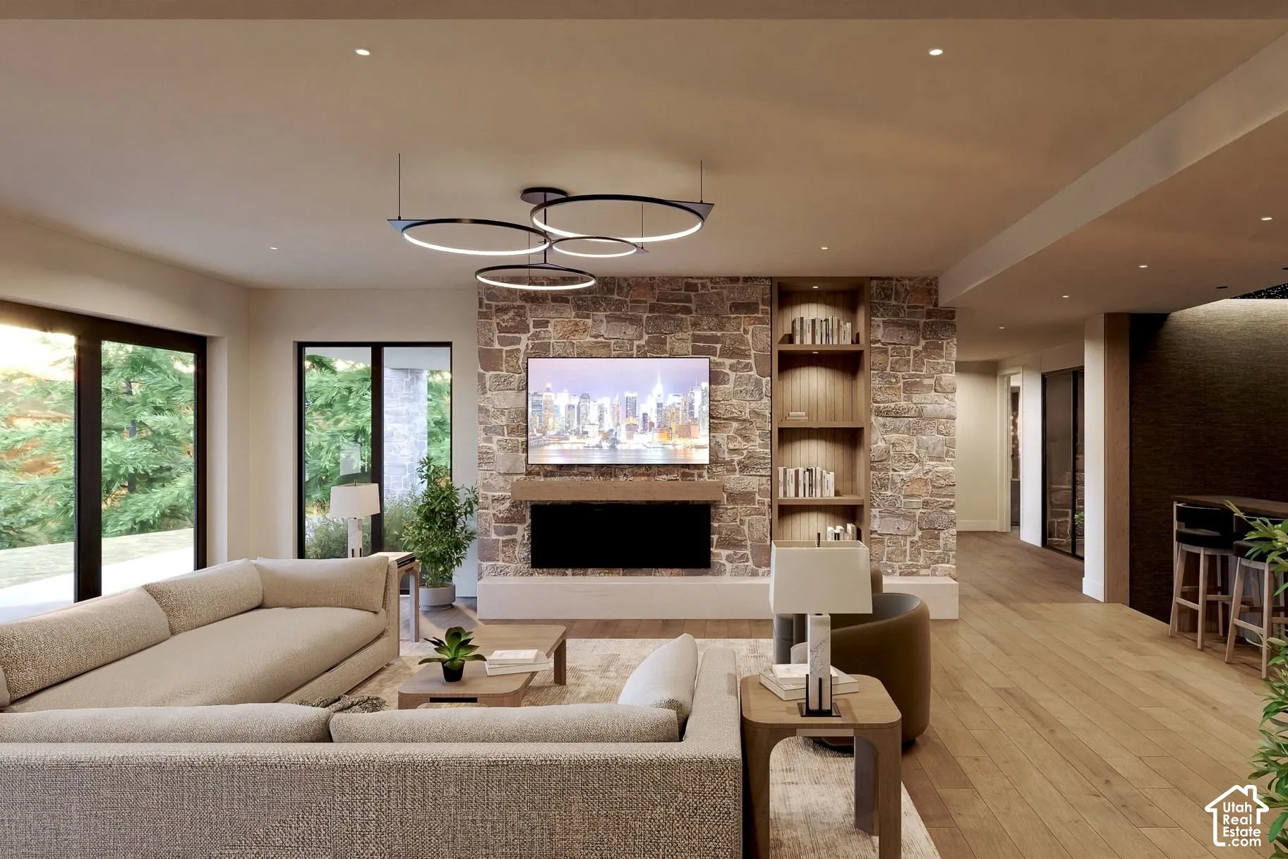 Floor-to-ceiling natural stone fireplace surround, custom built-in shelving, wood-finish flooring, modern multi-ring pendant lighting, and expansive glass sliding doors