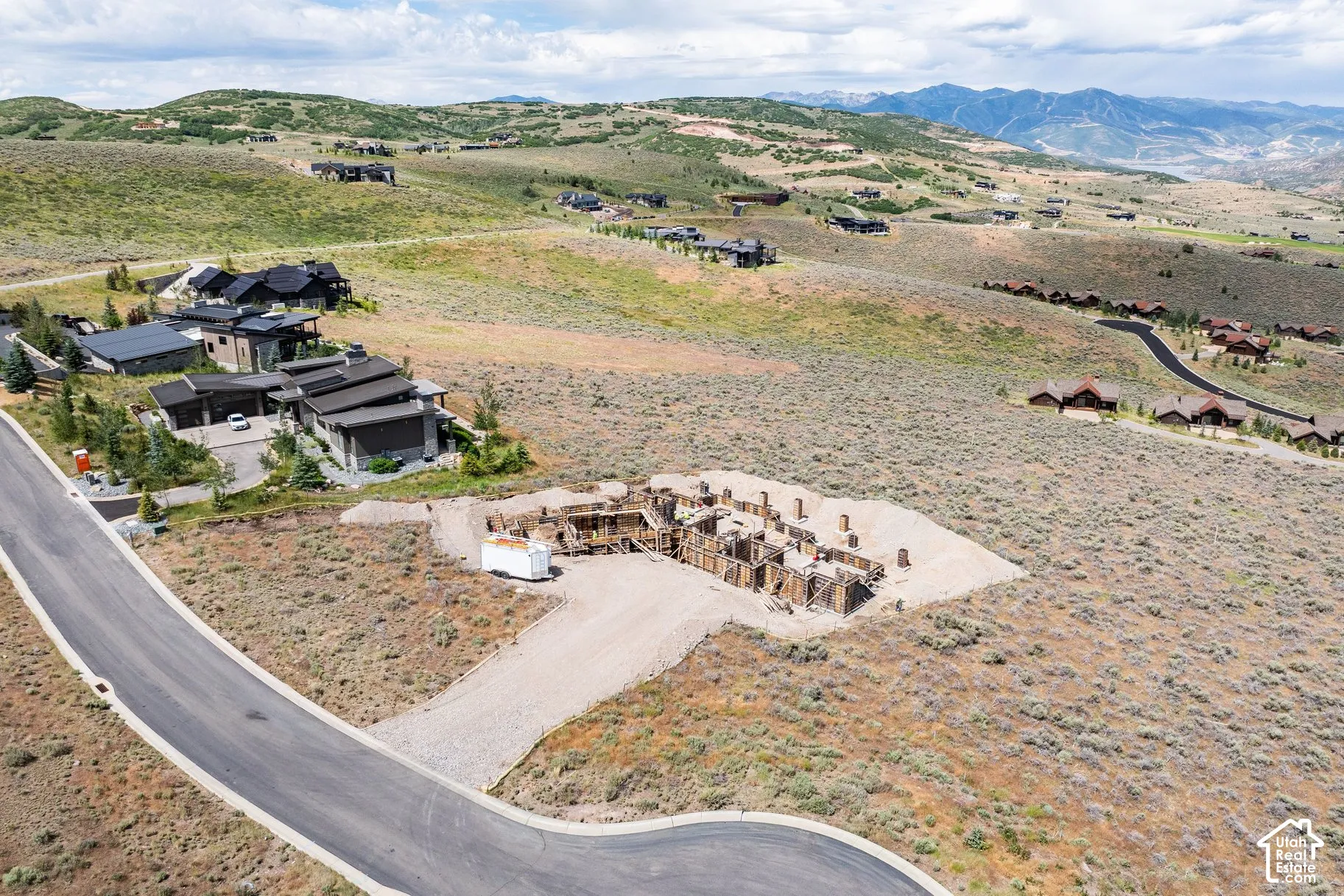 Hillside building lot featuring a poured concrete foundation, gravel driveway access, and mountainous terrain