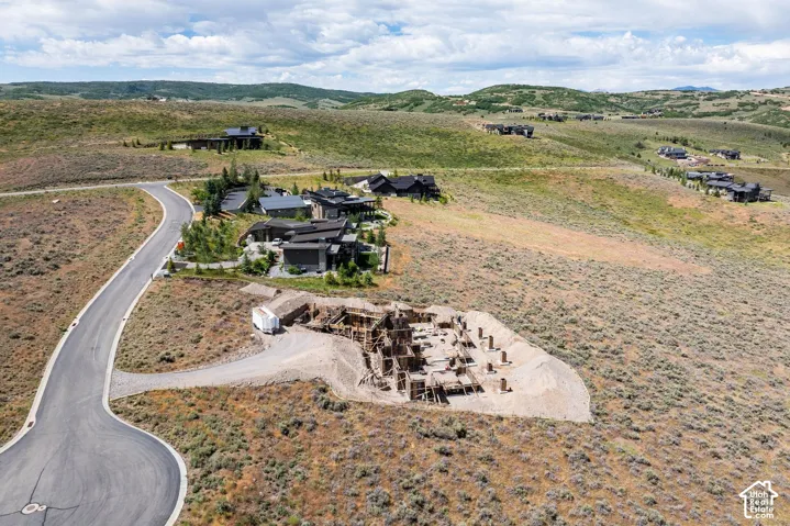 Elevated building site featuring foundation footings, paved cul-de-sac access, and expansive mountain terrain surroundings