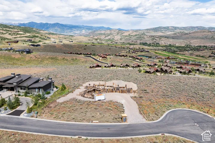 Expansive undeveloped parcel featuring prominent mountain terrain, gravel drive access, and paved street frontage