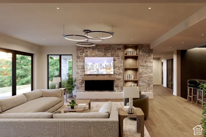 Floor-to-ceiling natural stone fireplace surround, custom built-in shelving, wood-finish flooring, modern multi-ring pendant lighting, and expansive glass sliding doors