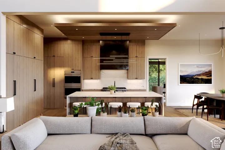 Kitchen featuring custom wood cabinetry, central island with stone countertop, ceiling-mounted recessed lighting, and integrated stainless steel double wall ovens