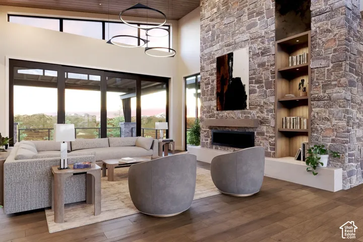 Double-height ceiling with wood-paneled accents, floor-to-ceiling stone fireplace, built-in shelving, multi-panel sliding glass doors, and modern circular pendant lighting