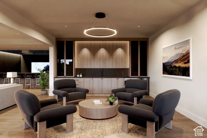 Built-in cabinetry with wood-finish flat-panel doors, integrated under-cabinet lighting, dark stone backsplash, modern circular pendant fixture, and wood-finish flooring