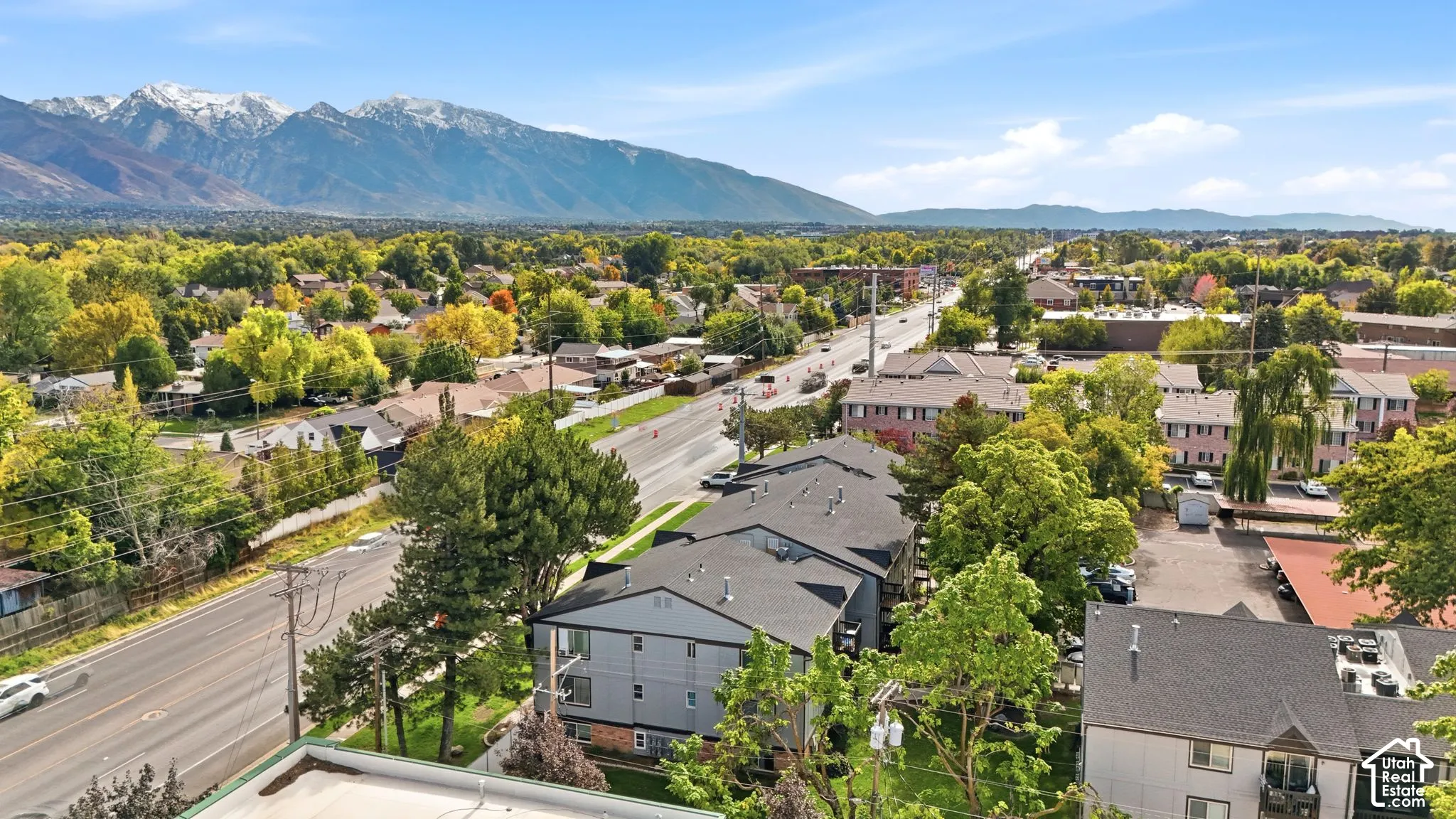 Aerial perspective of multi-story residential buildings with shingled roofing, set against a prominent backdrop of snow-capped mountain peaks