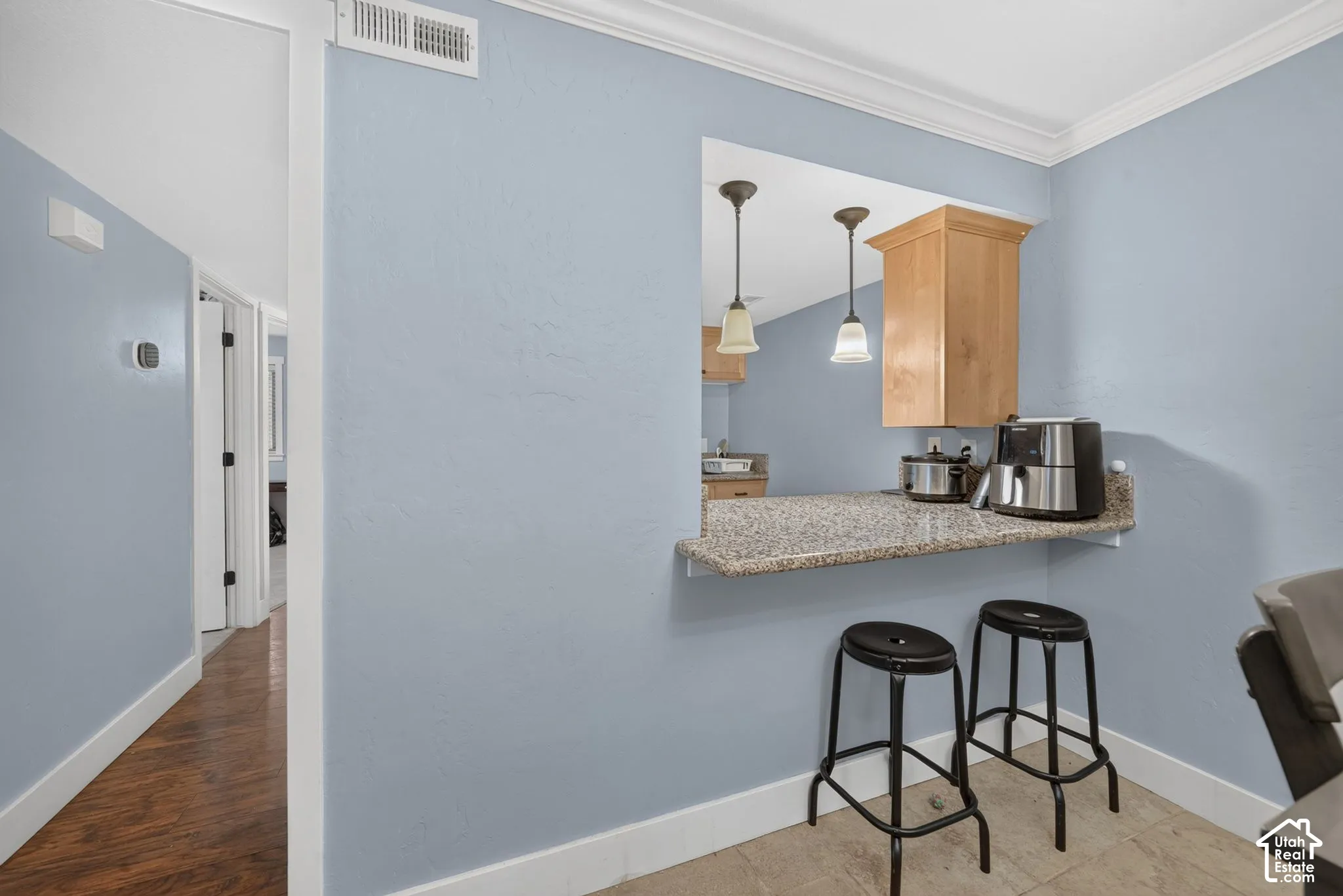 Pass-through window featuring a stone-composite countertop, wood-finish cabinetry, and dual pendant lighting fixtures