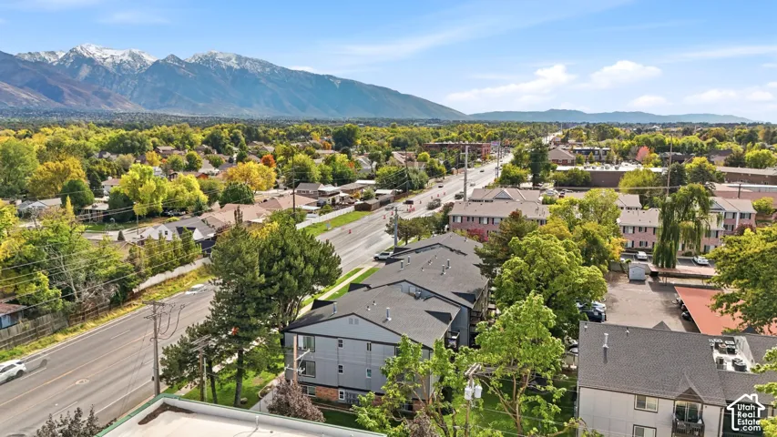 Aerial perspective of multi-story residential buildings with shingled roofing, set against a prominent backdrop of snow-capped mountain peaks