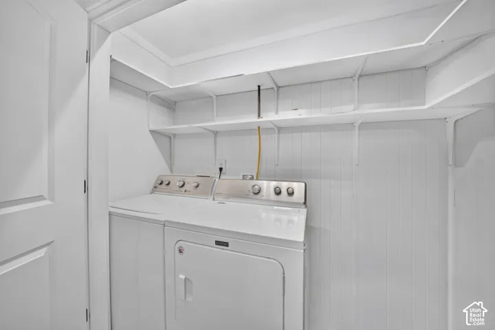 Laundry space featuring vertical paneled wall treatments and tiered built-in shelving