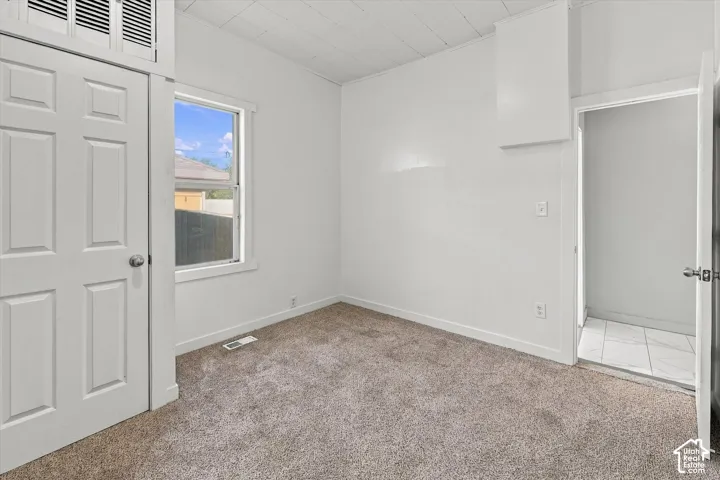 Interior room featuring neutral carpeting, a single-panel door with transom window, and white interior trim
