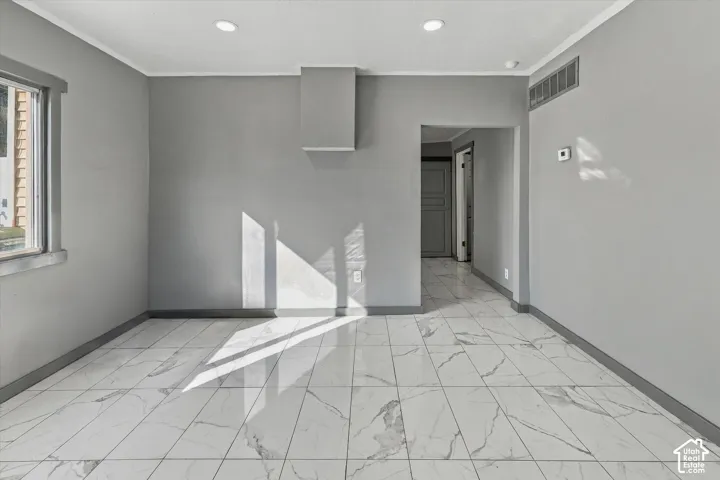 Large-format tile flooring, recessed ceiling lighting, and a central wall-mounted architectural feature