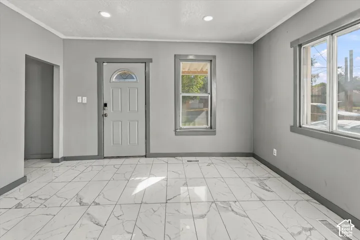 Interior featuring large-format stone-patterned tile flooring, recessed ceiling lighting, and a front entry door with a decorative glass inlay