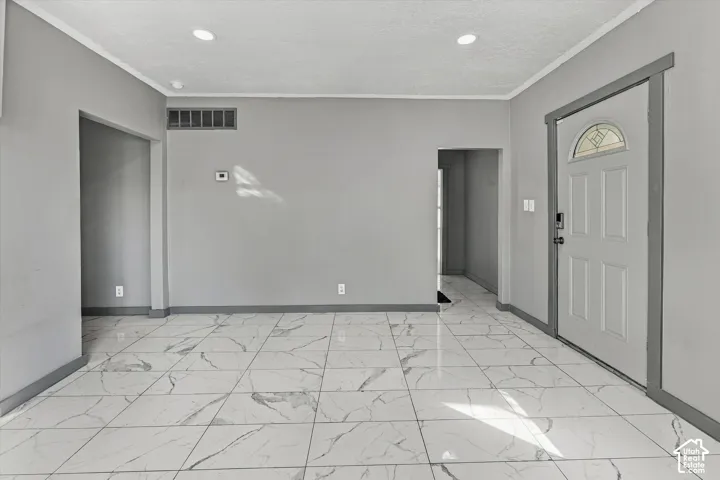 Interior space featuring large-format tile flooring with a neutral veined pattern, recessed ceiling lighting, and a six-panel entry door with an arched glass inset