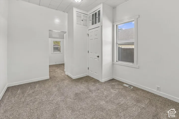 Interior space featuring wall-to-wall carpeting, high-panel ceilings, built-in cabinetry, and white-trimmed windows