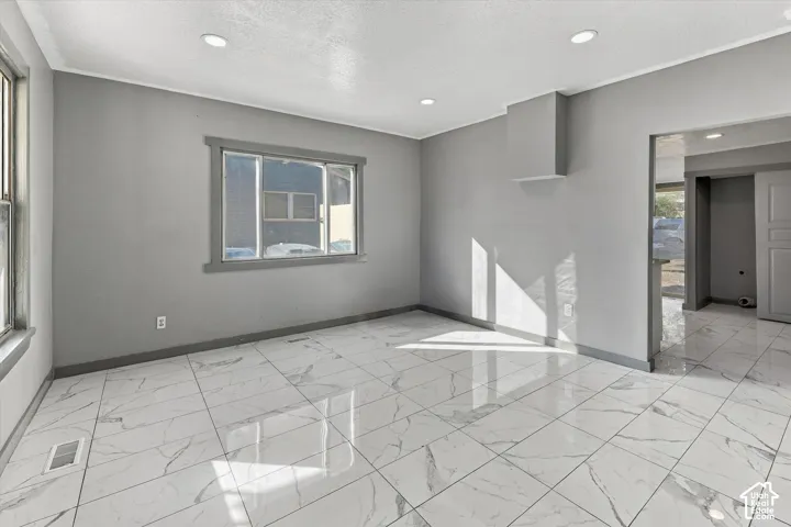 Large-format tile flooring with a veined pattern, recessed ceiling lighting, and thick-profile window trim