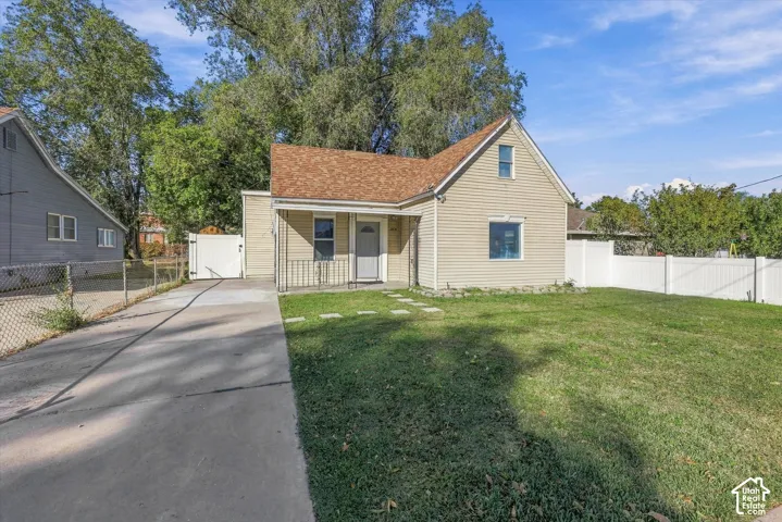 Single-story residence featuring light-colored horizontal siding, an asphalt shingle roof, a concrete driveway, and white vinyl perimeter fencing
