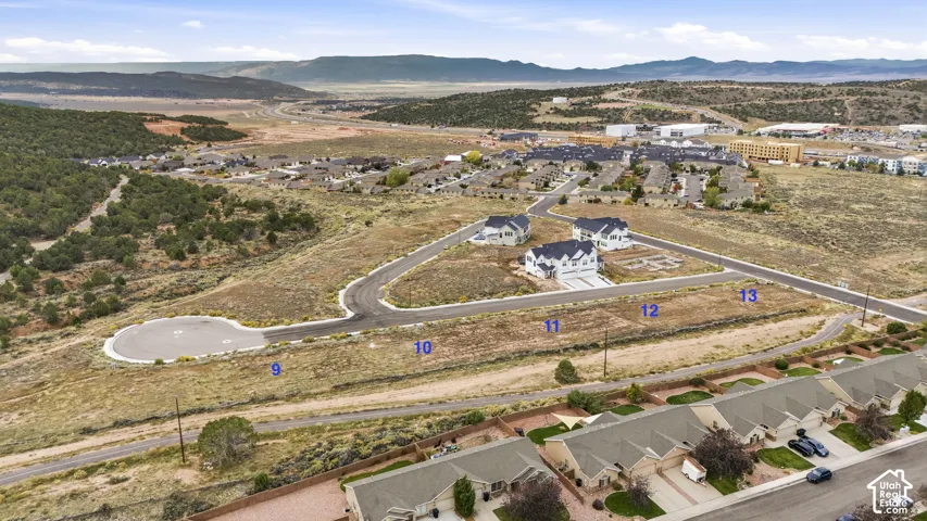 Aerial perspective of five contiguous parcels featuring expansive desert terrain, paved cul-de-sac access, and a prominent mountain range backdrop