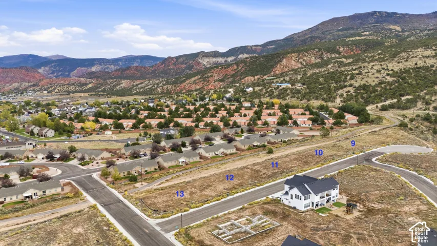 Aerial perspective of residential land parcels featuring paved road access, utility infrastructure, and mountain terrain backdrop