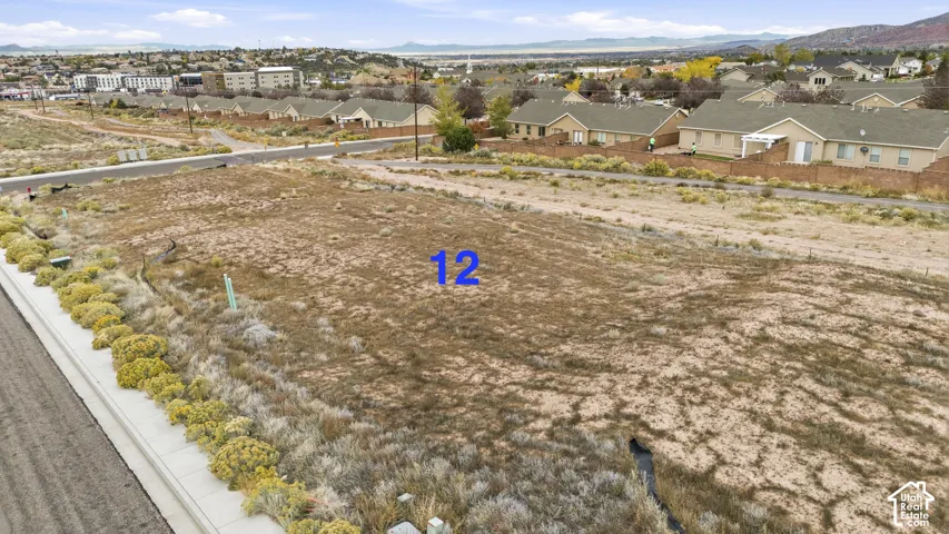 Vacant residential lot featuring paved street frontage, concrete curbing, and native desert landscaping with a mountain backdrop