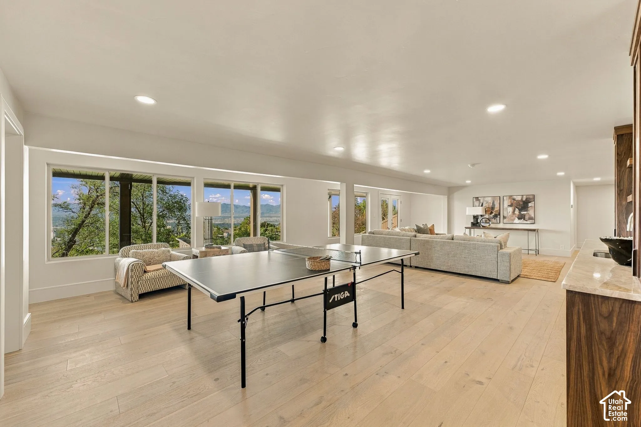 Open-concept interior featuring wood-finish flooring, recessed lighting, and expansive windows showcasing a mountain backdrop