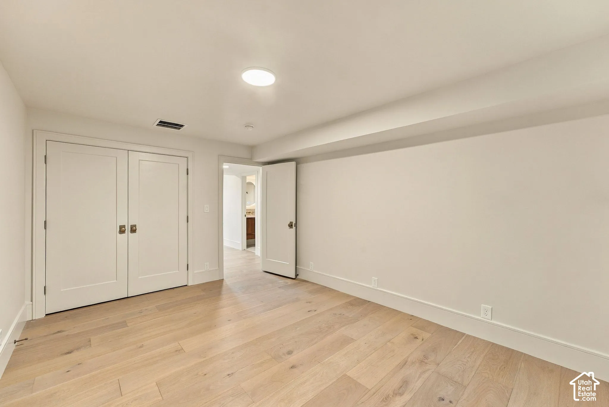Room featuring wood-finish flooring, dual-panel closet doors, and recessed lighting