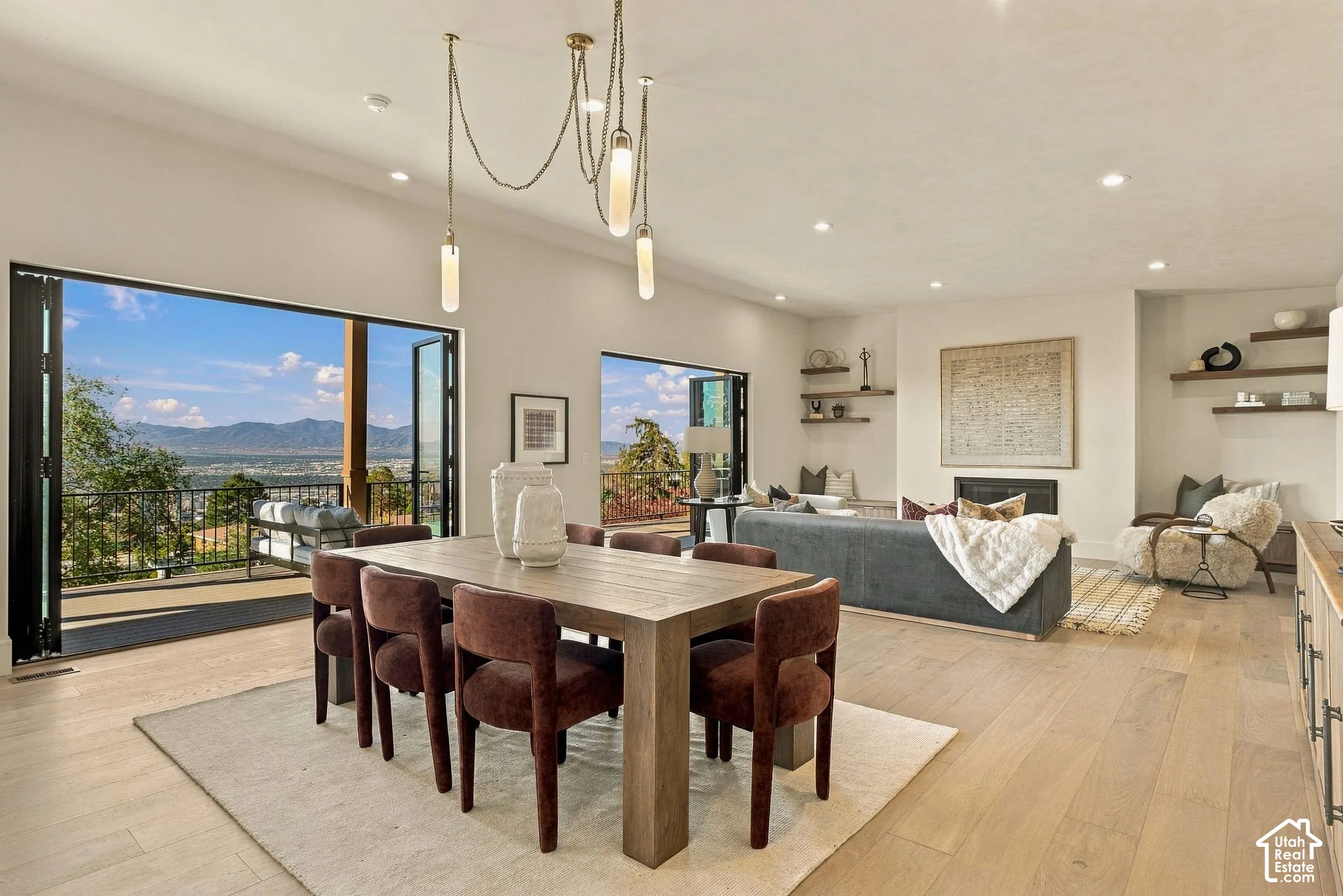 Multipanel folding glass doors, wood-finish flooring, recessed lighting, built-in shelving, and a mountain backdrop
