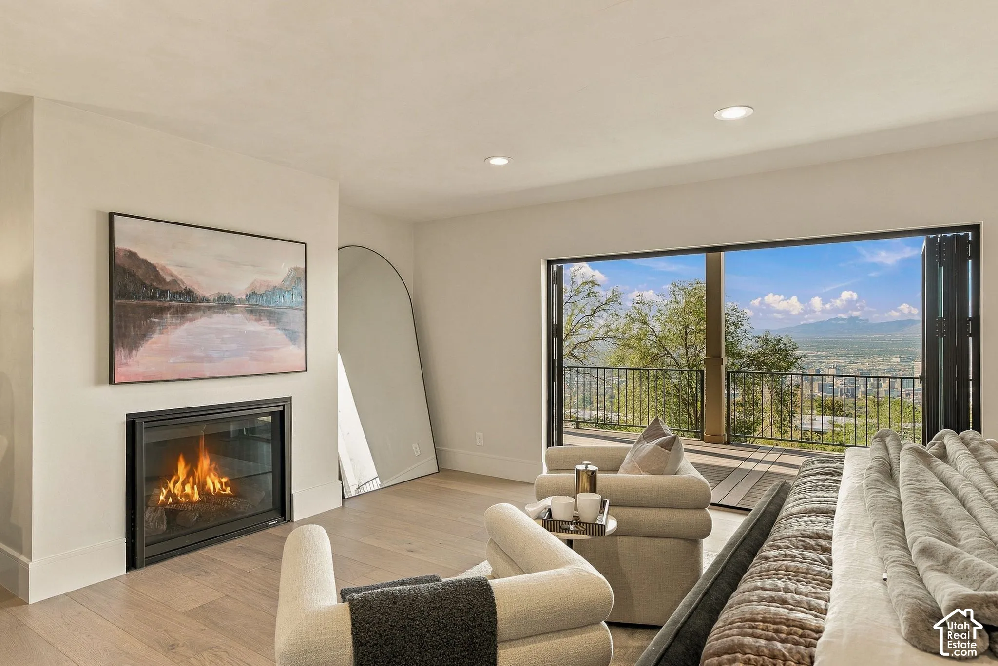 Built-in fireplace with a black surround, wood-finish flooring, recessed lighting, and folding glass patio doors opening to a deck