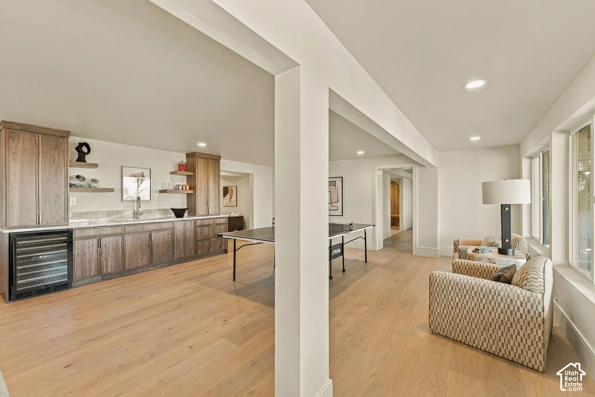 Custom built-in bar featuring stained wood cabinetry, stone countertops, undermount sink, and integrated wine refrigerator, set over wood-finish flooring