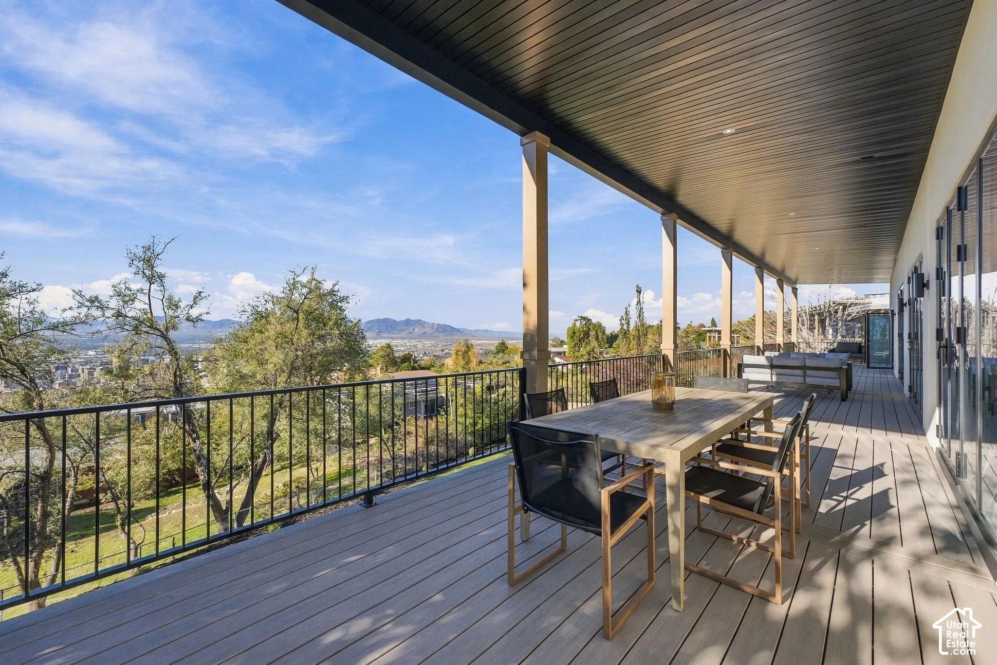 Covered deck featuring composite decking, metal railings, and mountain scenery