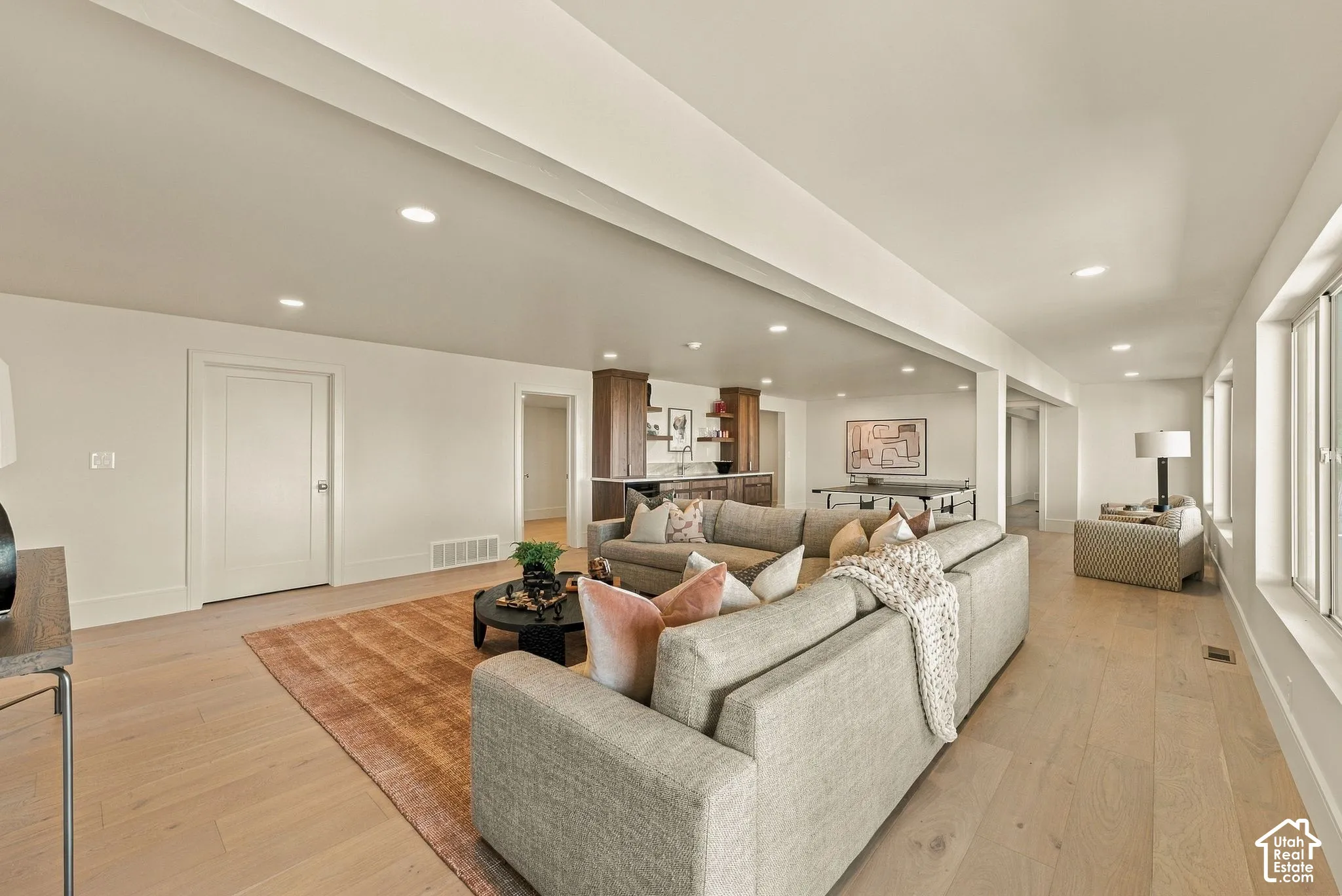Expansive interior space featuring wood-finish flooring, recessed lighting, and a built-in wet bar with wood cabinetry and open shelving