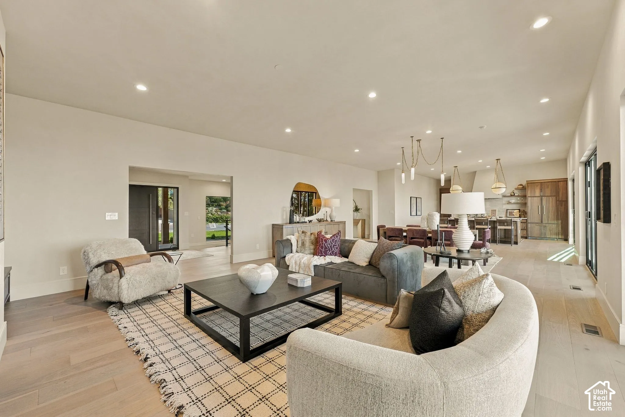 Open-concept interior featuring light wood-finish flooring, recessed lighting, and custom pendant light fixtures