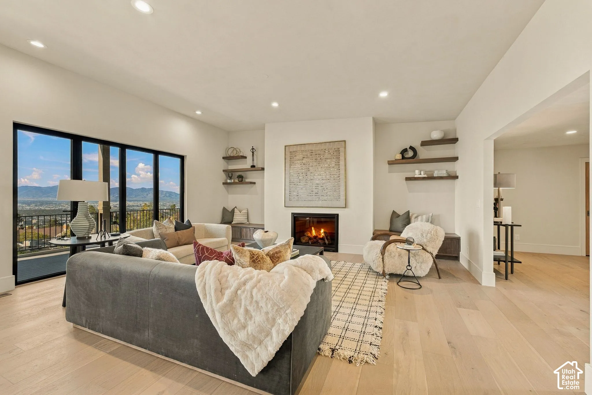 Living area featuring wood-finish flooring, recessed lighting, a built-in fireplace, wall-mounted shelving, and floor-to-ceiling windows