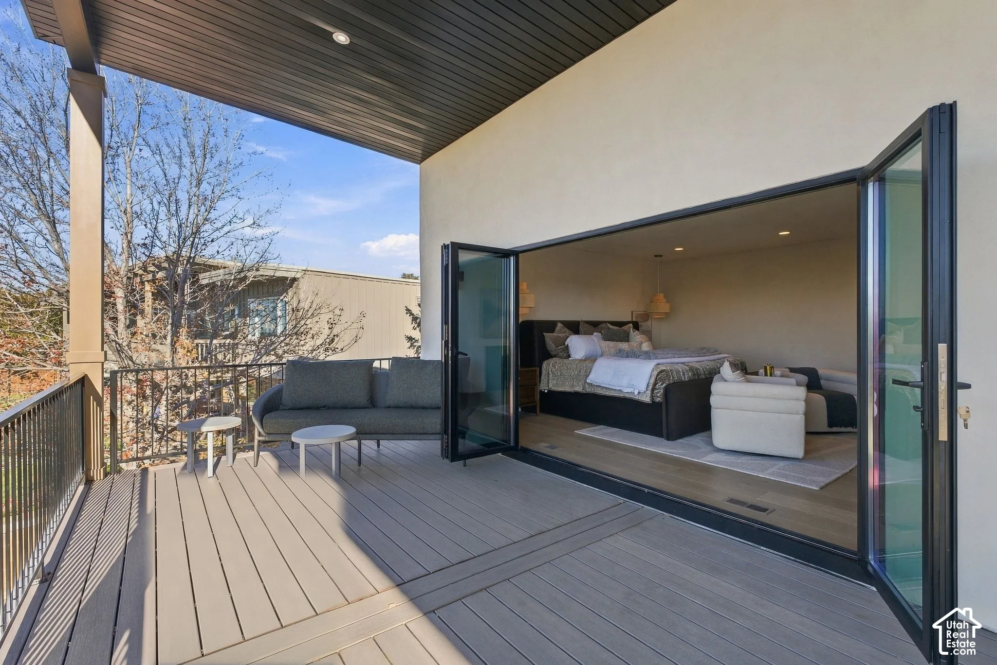 Covered balcony with composite decking and metal railing, featuring multi-panel folding glass doors