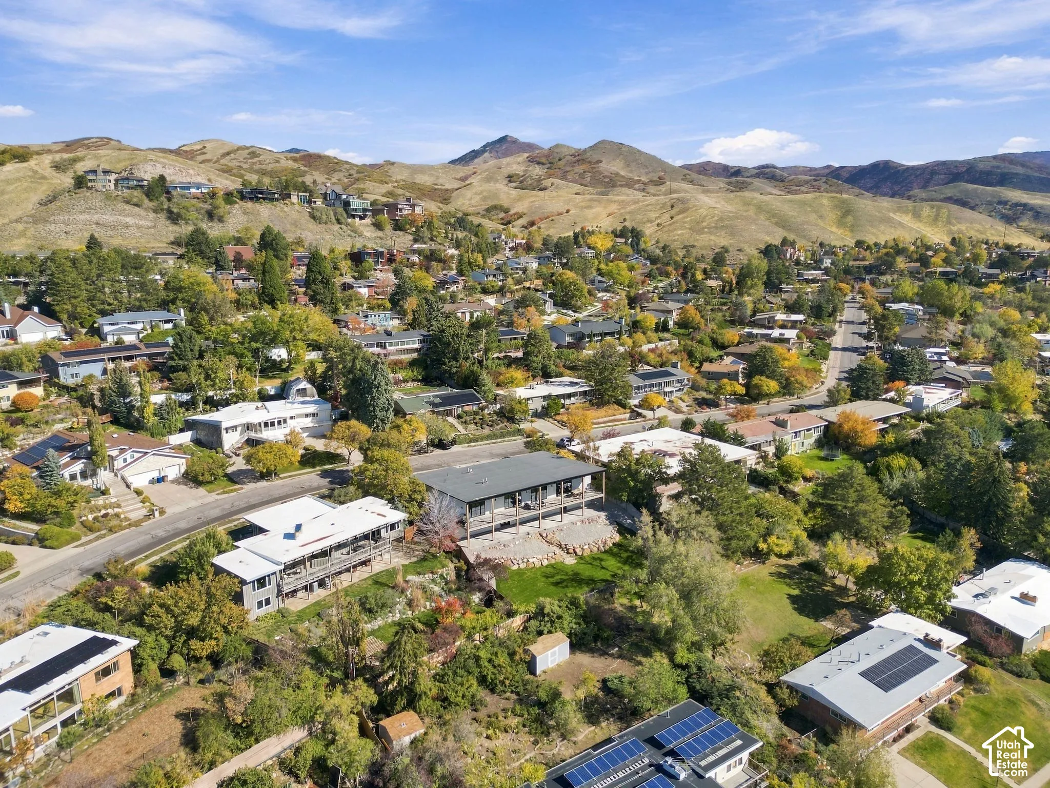 Aerial perspective of the property featuring a tiered landscape, rear deck, and prominent mountain backdrop