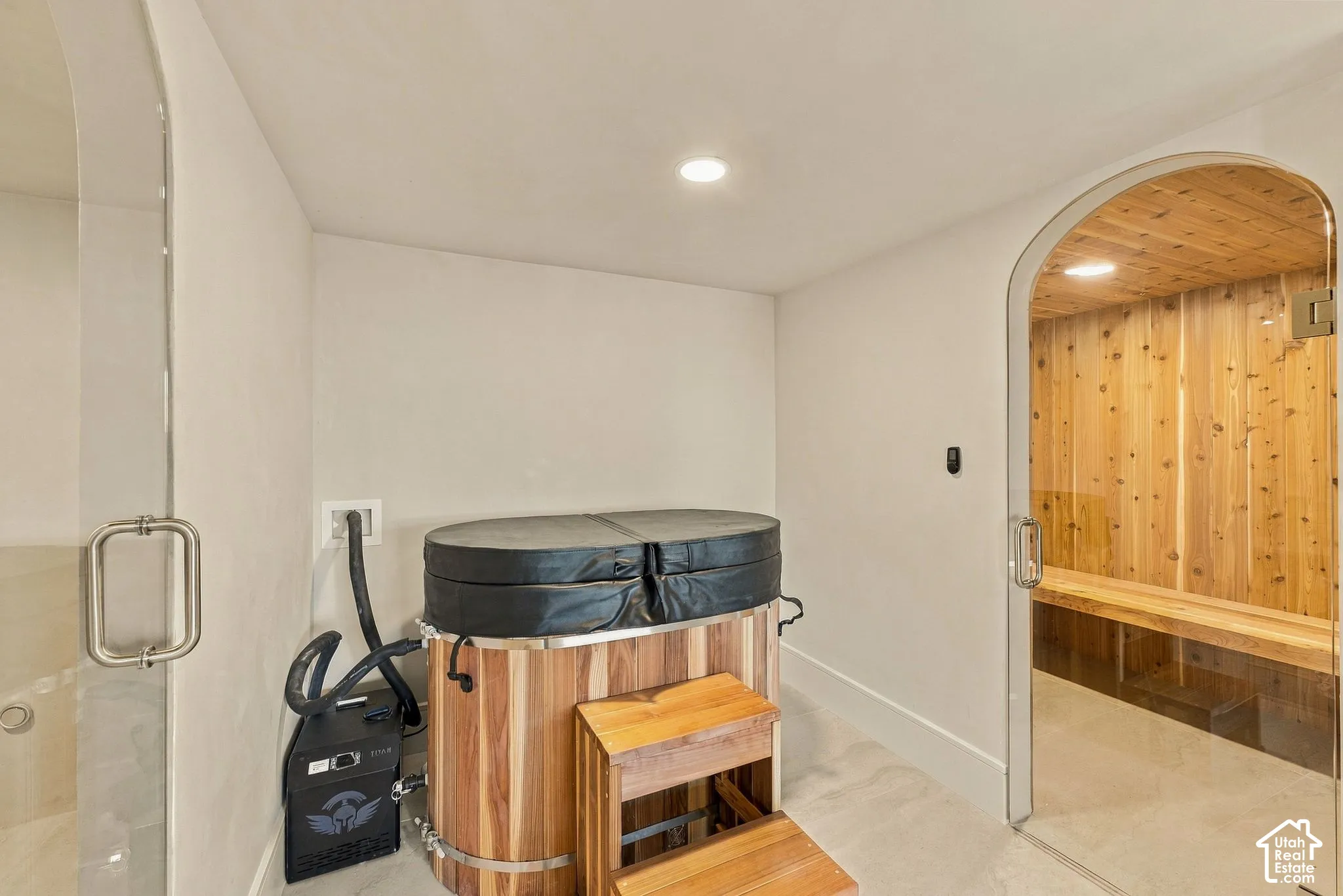 Spa room featuring a wood-clad sauna with glass arched door, a standalone cedar tub, and an enclosed glass shower